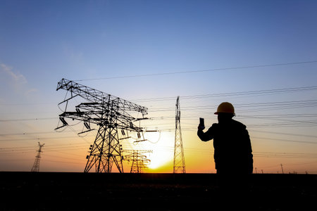 In the evening, electricity workers and pylon silhouette, Power workers at work