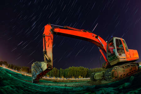 Excavator is under the stars, Digger and star tracks at nightの写真素材