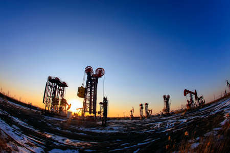 Oil field site, in the evening, oil pumps are running, Silhouette of beam pumping unitの写真素材