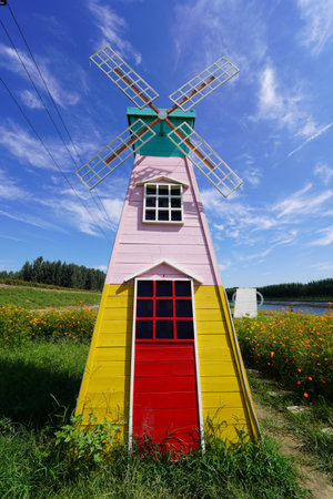 Beautiful windmill under the blue sky, the foreground is blooming flowersの写真素材