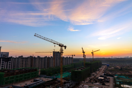 The construction site is in the morning. In the morning, the tower hangs over the construction site, , Tower cranes build residential buildingsの写真素材