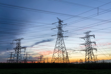 In the evening, high voltage towers silhouette and a beautiful sunsetの写真素材