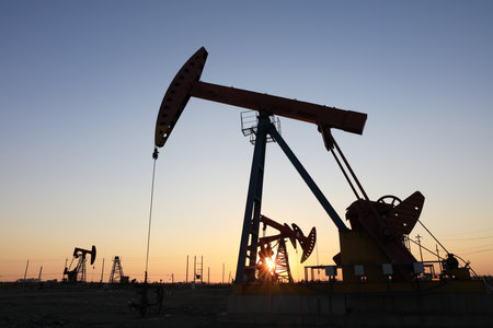 Oil field site, in the evening, oil pumps are running, Silhouette of beam pumping unitの写真素材