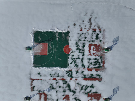 The school's basketball court in winter, the basketball court is covered with snow, school rubber basketball courtの写真素材