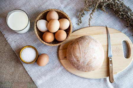 Still life bread eggs salt and milk on wooden plates on a background in warm colorsの写真素材