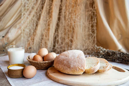 Still life bread eggs salt and milk on wooden plates on a background in warm colorsの写真素材