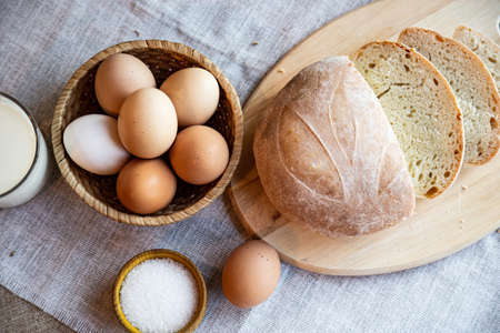 Still life bread eggs salt and milk on wooden plates on a background in warm colorsの写真素材