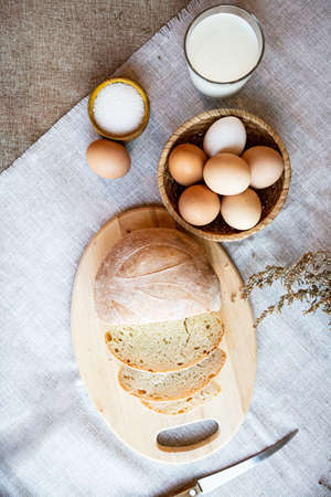 Still life bread eggs salt and milk on wooden plates on a background in warm colorsの写真素材
