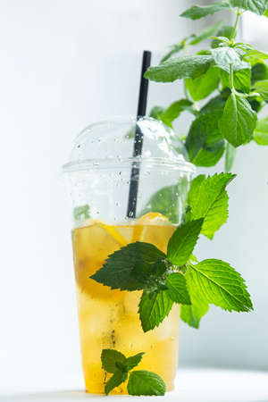 Green tea with iced lemon and lemon balm in a plastic glass on a white backgroundの写真素材