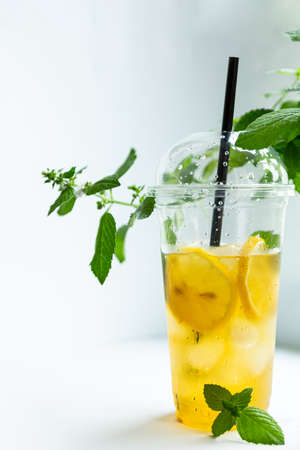 Green tea with iced lemon and lemon balm in a plastic glass on a white backgroundの写真素材