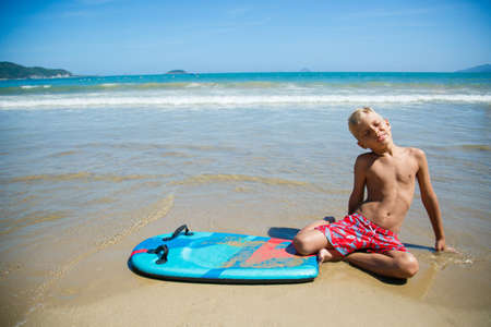 Boy with bodyboard playing on the seashoreの写真素材