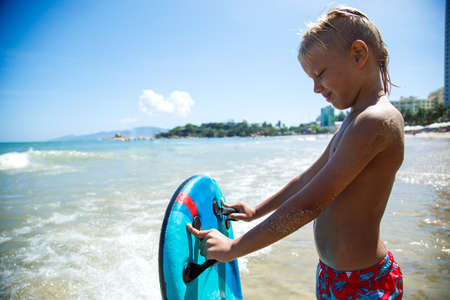 Boy with bodyboard playing on the seashoreの写真素材