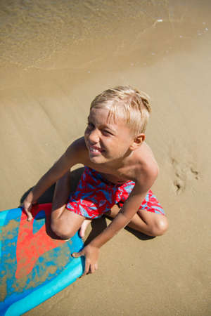 Boy with bodyboard playing on the seashoreの写真素材