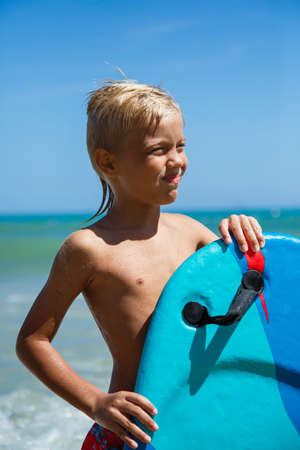 Boy with bodyboard playing on the seashoreの写真素材