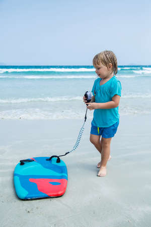 Kid with bodyboard playing on the background of the sea on the beachの写真素材