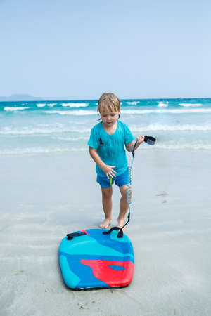 Kid with bodyboard playing on the background of the sea on the beachの写真素材