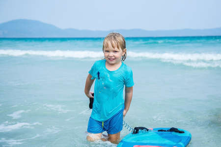 Kid with bodyboard playing on the background of the sea on the beachの写真素材
