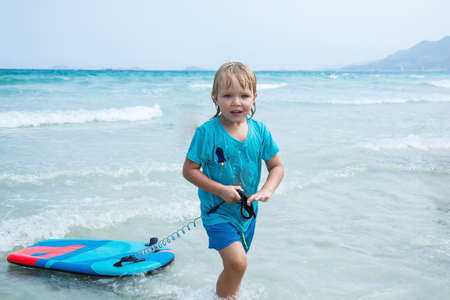 Kid with bodyboard playing on the background of the sea on the beachの写真素材