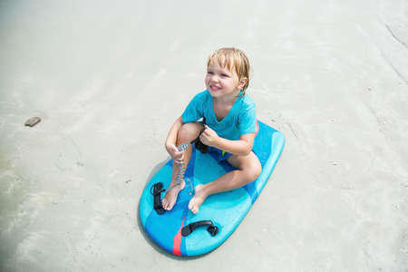 Kid with bodyboard playing on the background of the sea on the beachの写真素材