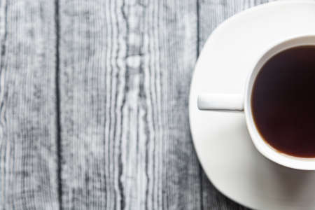 White cup with coffee on a white saucer on a gray wood backgroundの写真素材