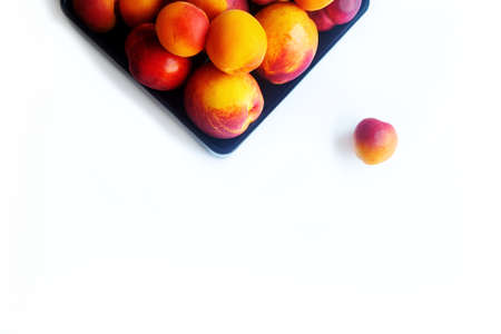 Peaches apricots and nectarines in a black plate on a white backgroundの写真素材