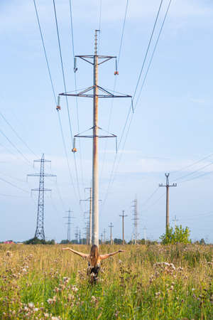 Girl in the field on the background of power linesの写真素材