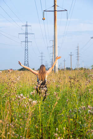 Girl in the field on the background of power linesの写真素材