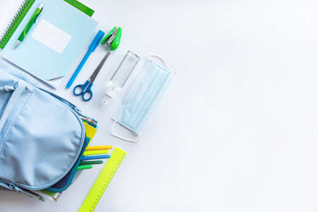 Back to school after coronavirus pandemic. Backpack, stationery, antiseptic, face mask on a white background. (notebooks, pens, felt-tip pens, scissors, stapler, sanitizer, covid-19)の写真素材