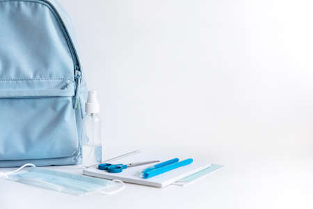 Back to school after coronavirus pandemic. Backpack, stationery, antiseptic, face mask on a white background. (notebooks, pens, felt-tip pens, scissors, stapler, sanitizer, covid-19)の写真素材