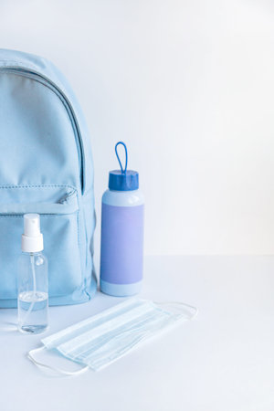 Backpack, water bottle, face mask and antiseptic on a white background. Walking concept.