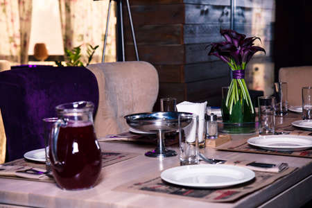Vase with purple flowers on a table in a restaurant interiorの写真素材
