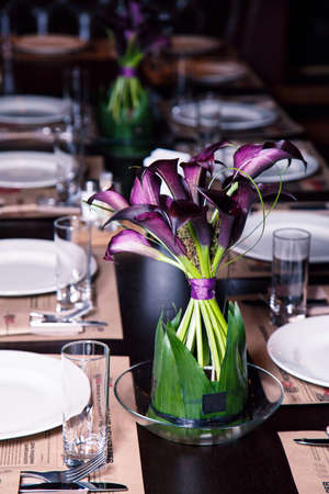 Vase with purple flowers on a table in a restaurant interiorの写真素材