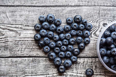 Heart made of blueberries on wooden table. top viewの写真素材