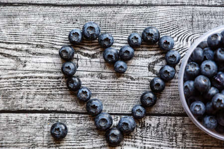 Heart made of blueberries on wooden table. top viewの写真素材
