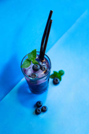 Blueberry juice with ice and mint. Cocktail with reusable iron tubes on a blue background.の写真素材