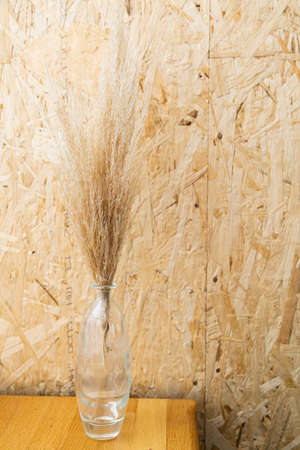 Dried flowers in a glass vase on a wooden background. warm colors.の写真素材