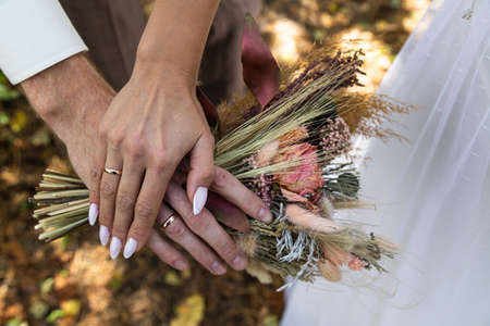 The bride's bouquet of dried flowers in the hands of the newlyweds. Bohoshik, vintageの写真素材