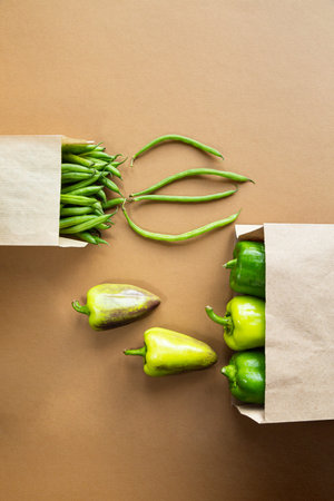 Green beans and paprika in a craft paper bag on a brown background. Harvest organic healthy food