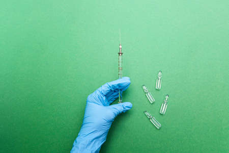 A doctor in a medical glove holds a syringe with a vaccine and vial with a vaccine. Healthcare conceptの写真素材