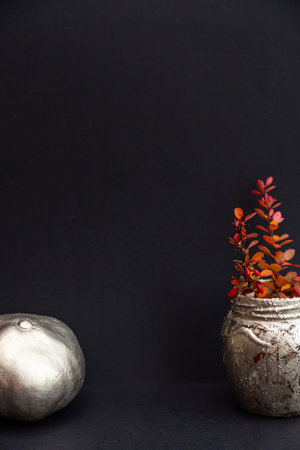 Festive Halloween composition. Still life of pumpkin painted with silver and gold paint, pink-orange...