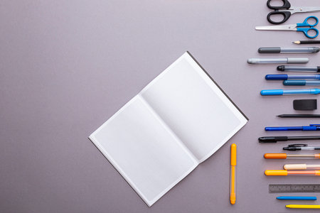 An empty squared notebook and a lot of stationery on a gray background. Education or business...