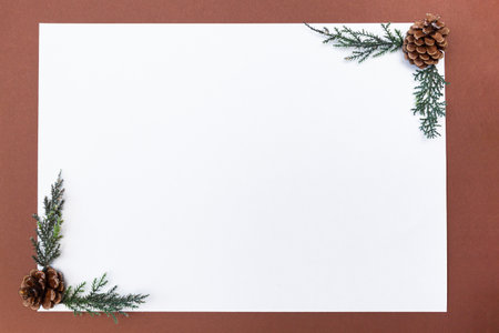 Blank sheet of paper on a brown background, composition with pine cones. Winter background with space for text, mock up.の写真素材