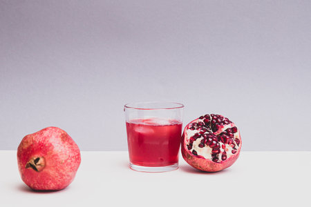 Minimalistic still life with pomegranate fruit and pomegranate juice in a glassの写真素材