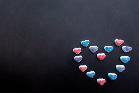 The heart is made of colored gummy hearts on a black background. Sweet valentine's day conceptの写真素材