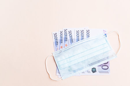 500 euro banknotes and a protective medical face mask on a light background. Health protection and financial well-being concept.の写真素材