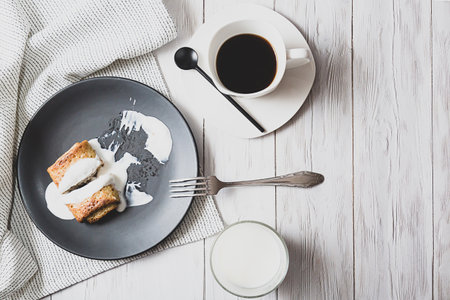 Pancakes with filling and sour cream, a glass of milk and a cup of black coffee on a light table. Rustic breakfast with copy space top viewの写真素材