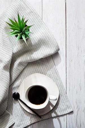 Minimalistic still life in white. A cup of coffee, a light napkin and a succulent plant in a white...