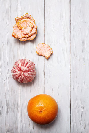 Grapefruit whole and peeled. Minimalistic flat lay on a light background with copy space. Healthy food conceptの写真素材