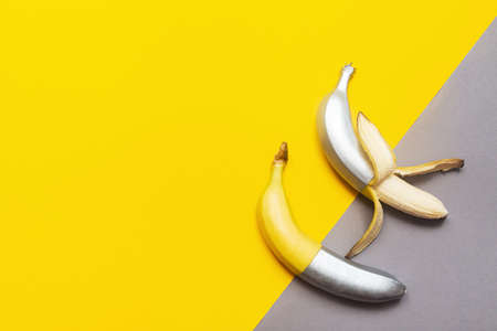 Painted silver peeled bananas on a yellow-gray background. Minimalistic abstract food imageの写真素材