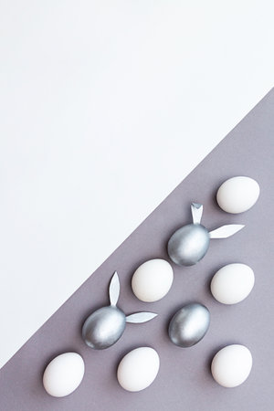 Eggs with bunny ears are colored silver and white eggs on white and grayの写真素材